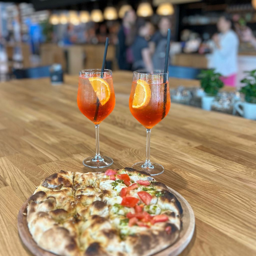Tavola di aperitivo con due spritz e una pizza
